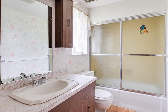 full bathroom with vanity, toilet, plenty of natural light, and enclosed tub / shower combo