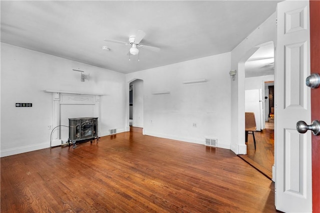 unfurnished living room with hardwood / wood-style flooring, ceiling fan, and a wood stove