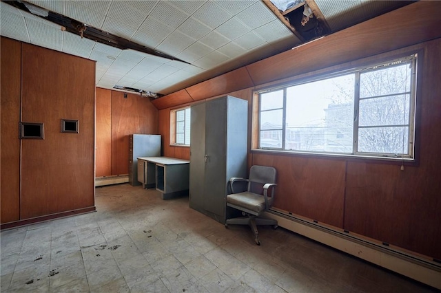 bonus room with a wealth of natural light, wooden walls, and a baseboard heating unit