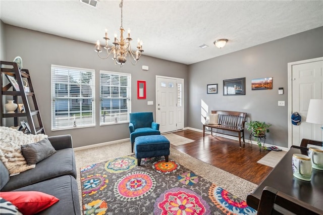 living room featuring hardwood / wood-style floors, a textured ceiling, and an inviting chandelier