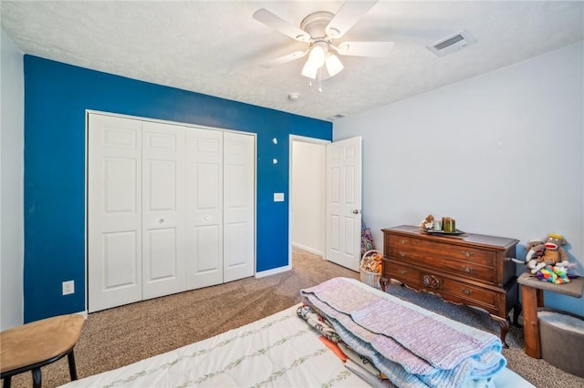 carpeted bedroom featuring a textured ceiling, a closet, and ceiling fan