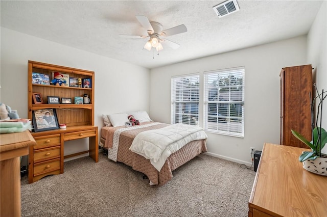 carpeted bedroom with ceiling fan and a textured ceiling