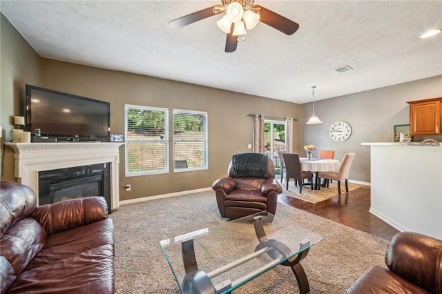 living room with a textured ceiling, dark hardwood / wood-style flooring, a wealth of natural light, and ceiling fan