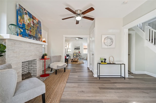 living room featuring ceiling fan, a fireplace, and hardwood / wood-style flooring