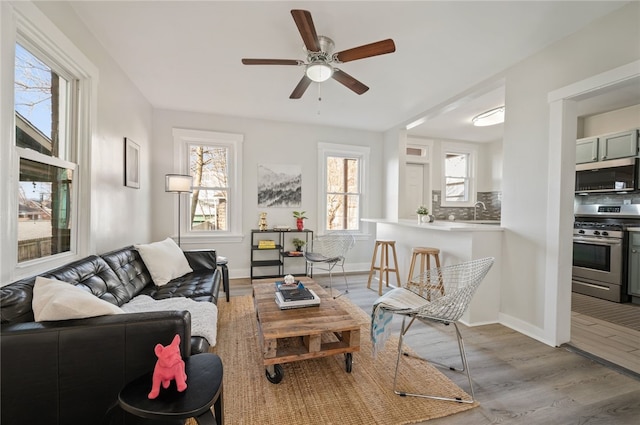 living room featuring ceiling fan, light wood-type flooring, and sink