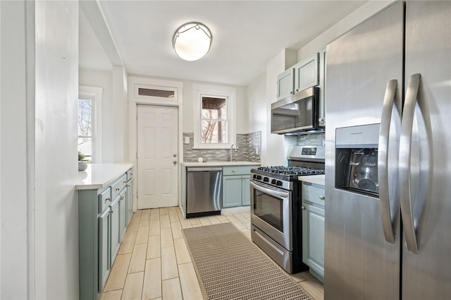 kitchen with a healthy amount of sunlight, decorative backsplash, sink, and stainless steel appliances