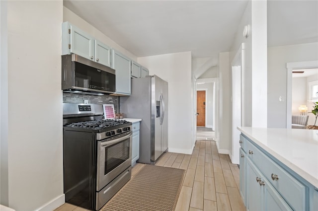 kitchen featuring blue cabinetry, stainless steel appliances, tasteful backsplash, and light hardwood / wood-style floors