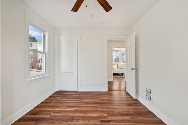 unfurnished bedroom featuring ceiling fan, dark wood-type flooring, and a closet