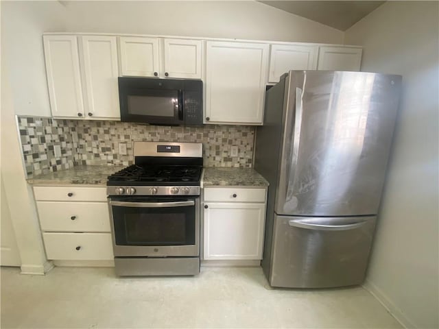 kitchen featuring decorative backsplash, appliances with stainless steel finishes, vaulted ceiling, dark stone countertops, and white cabinets