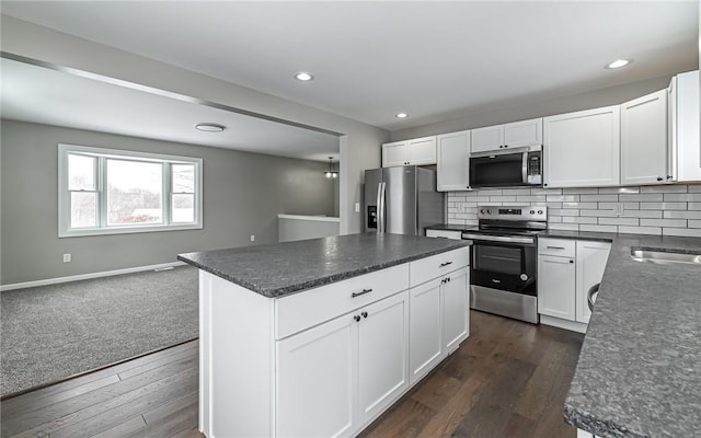 kitchen featuring white cabinetry, dark wood-type flooring, decorative backsplash, a kitchen island, and appliances with stainless steel finishes