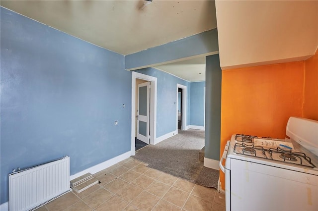 interior space featuring radiator, light tile patterned flooring, and white range with gas stovetop