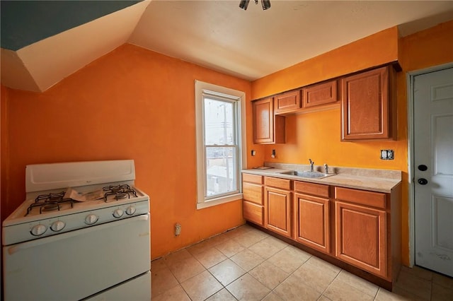 kitchen with light tile patterned flooring, lofted ceiling, white gas stove, and sink