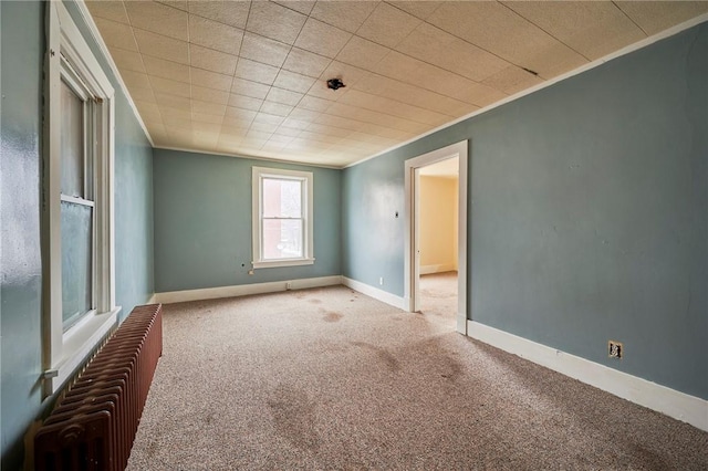 carpeted spare room with radiator heating unit and ornamental molding