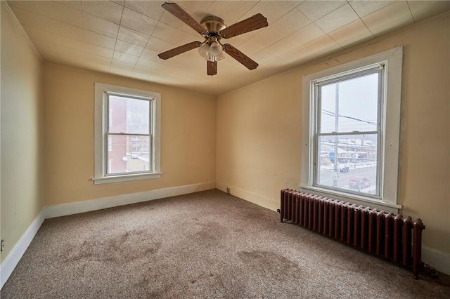 carpeted empty room with radiator and ceiling fan