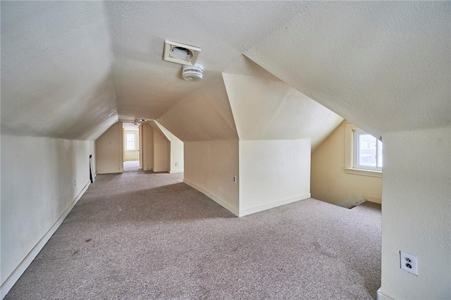 additional living space with carpet, a textured ceiling, and vaulted ceiling