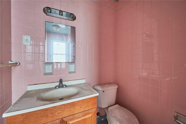 bathroom featuring vanity, tile walls, and toilet