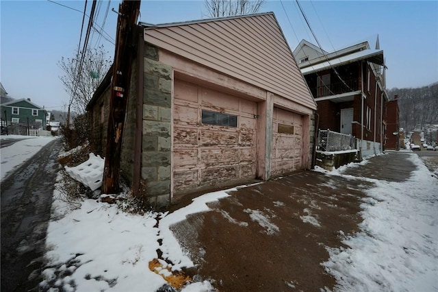 snow covered property featuring an outdoor structure and a garage