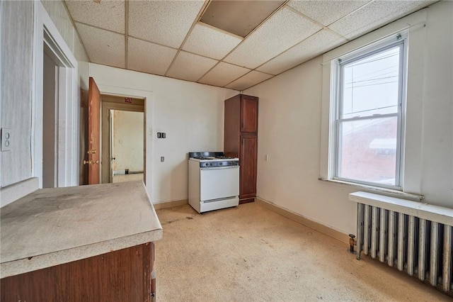 kitchen featuring a drop ceiling, light colored carpet, white gas range oven, and radiator