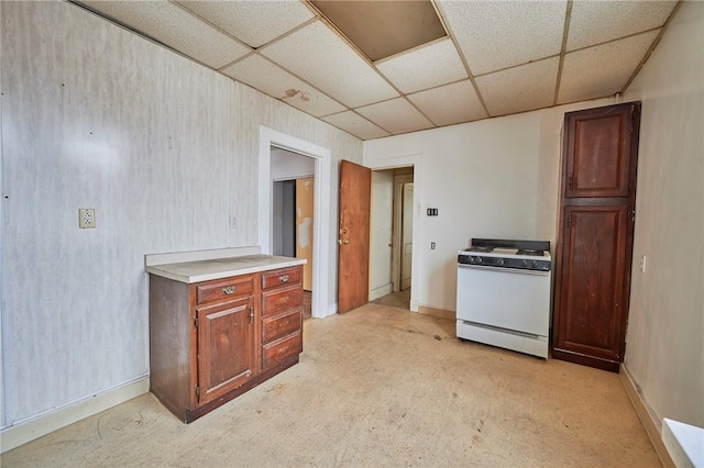 kitchen featuring light carpet, a drop ceiling, and white range with gas cooktop