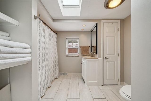 bathroom with vanity, a skylight, and toilet