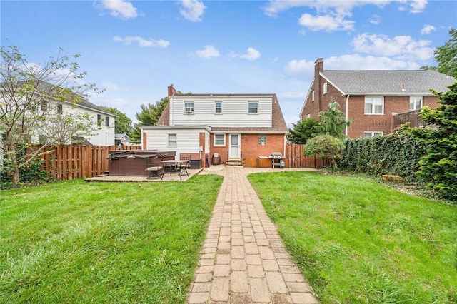 back of house featuring a yard, a patio, and a hot tub