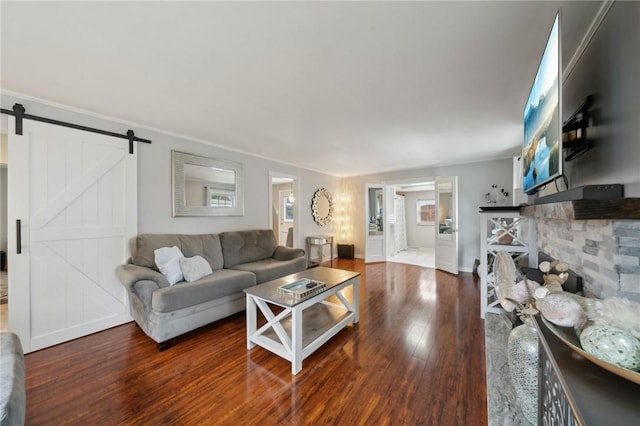 living room featuring a barn door, crown molding, and dark wood-type flooring