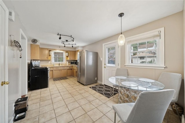 kitchen featuring light brown cabinets, sink, stainless steel appliances, decorative light fixtures, and light tile patterned floors