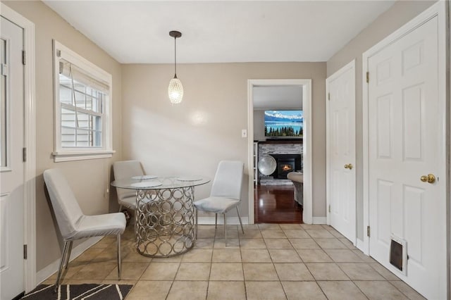 dining area with a stone fireplace and light tile patterned flooring