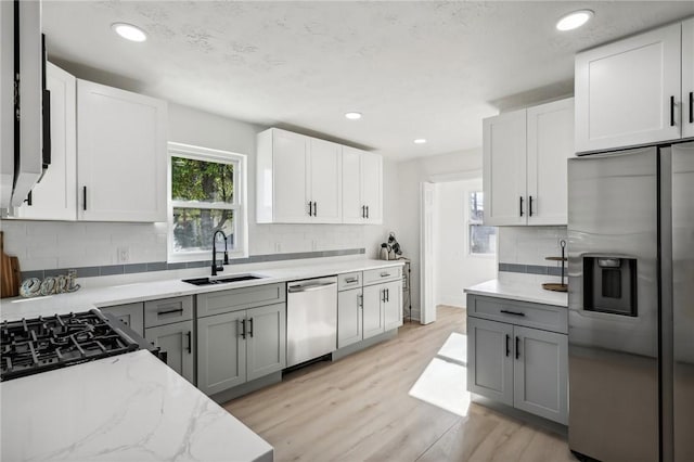 kitchen with white cabinetry, sink, stainless steel appliances, light hardwood / wood-style floors, and gray cabinets