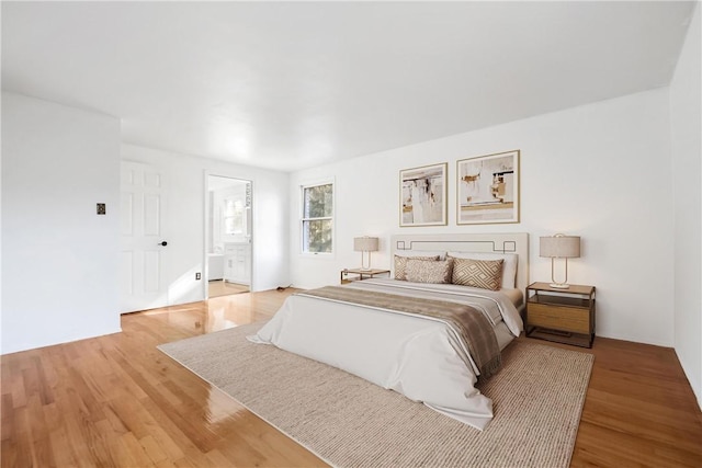 bedroom with light wood-type flooring and ensuite bathroom