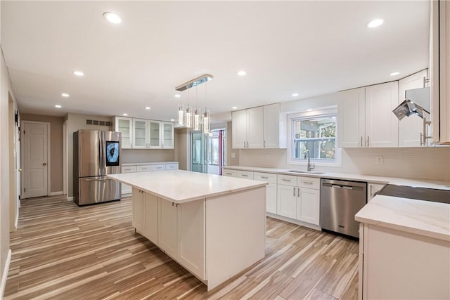 kitchen with white cabinetry, sink, a center island, hanging light fixtures, and appliances with stainless steel finishes