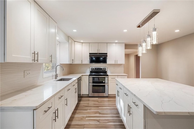 kitchen with hanging light fixtures, sink, white cabinets, and stainless steel appliances