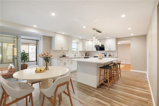 kitchen with a center island, decorative light fixtures, white cabinetry, and light hardwood / wood-style floors