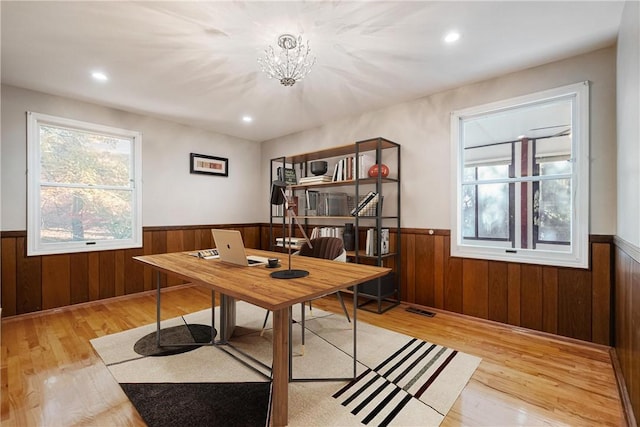 office with light hardwood / wood-style floors and a notable chandelier