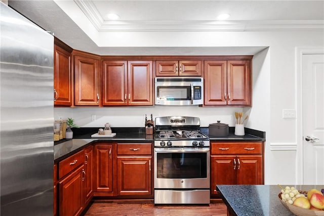 kitchen with dark stone counters, crown molding, and stainless steel appliances