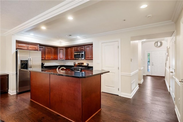 kitchen with a kitchen island with sink, dark wood-type flooring, ornamental molding, and appliances with stainless steel finishes