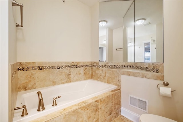 bathroom featuring toilet and tiled bath