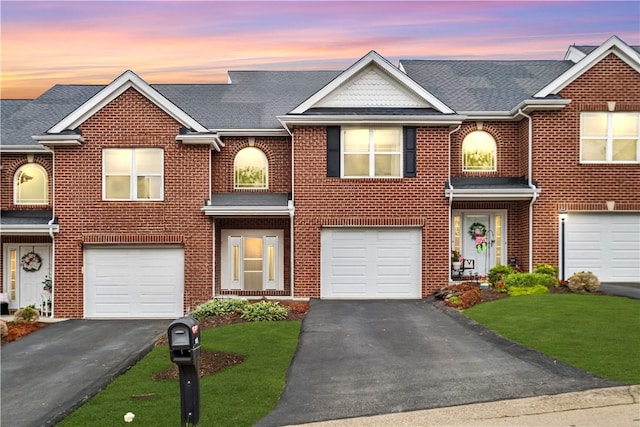 multi unit property featuring a garage and a lawn