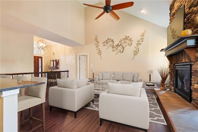 living room with a fireplace, dark hardwood / wood-style flooring, ceiling fan with notable chandelier, and high vaulted ceiling