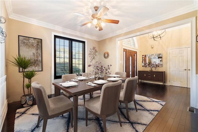 dining area with ceiling fan with notable chandelier, dark wood-type flooring, and crown molding