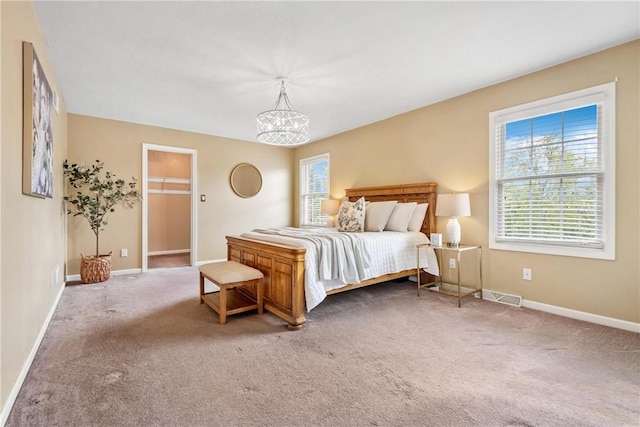 carpeted bedroom with a chandelier, a spacious closet, and a closet