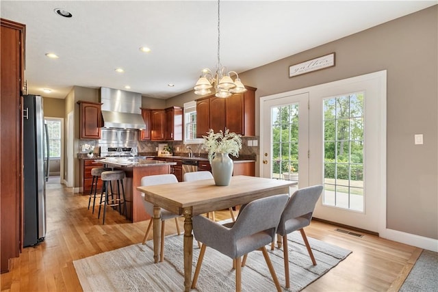 dining area with sink, light hardwood / wood-style floors, and an inviting chandelier