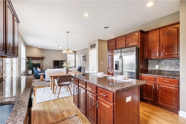 kitchen featuring a center island, stainless steel fridge, dark stone countertops, tasteful backsplash, and a healthy amount of sunlight