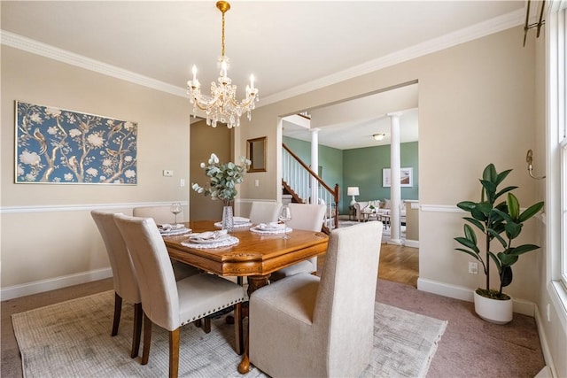 dining space with carpet flooring, ornate columns, ornamental molding, and a notable chandelier