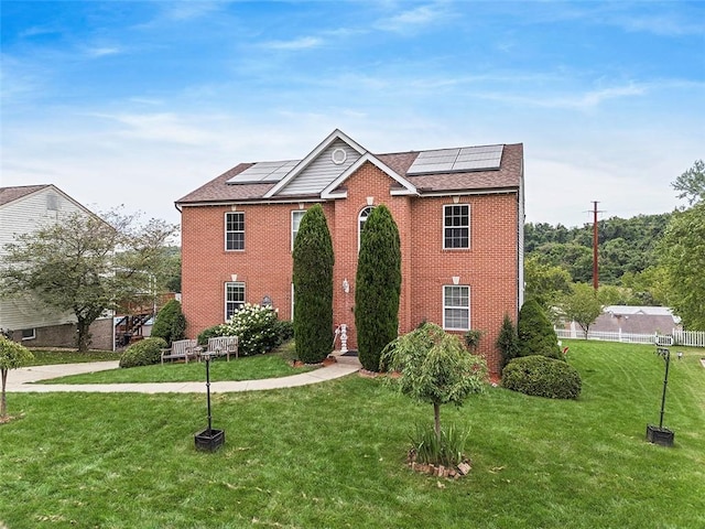 view of front of property with a front yard and solar panels