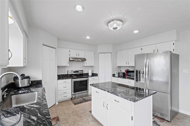 kitchen with a center island, sink, dark stone countertops, appliances with stainless steel finishes, and white cabinetry