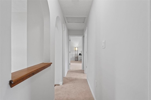 hallway featuring a textured ceiling and light carpet