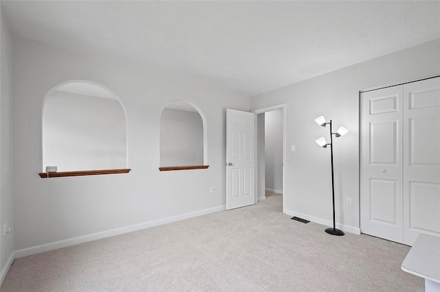 unfurnished bedroom featuring light carpet and a closet