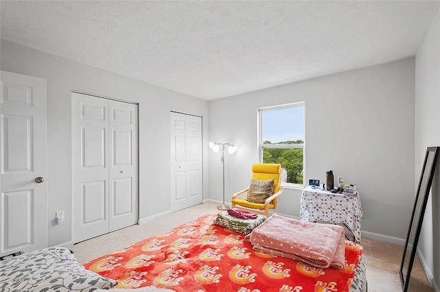 bedroom with a textured ceiling, carpet, and two closets