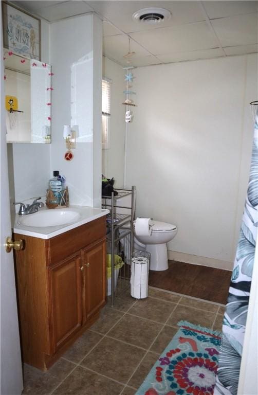 bathroom with a paneled ceiling, vanity, and toilet